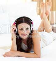 Smiling woman listening music lying on bed