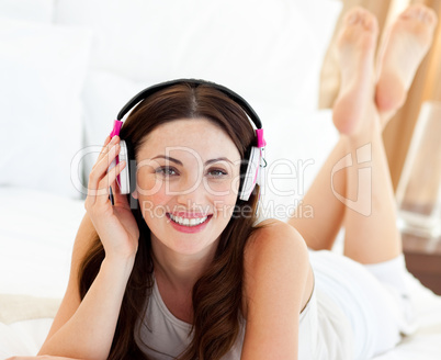 Beautiful woman listening music lying on bed