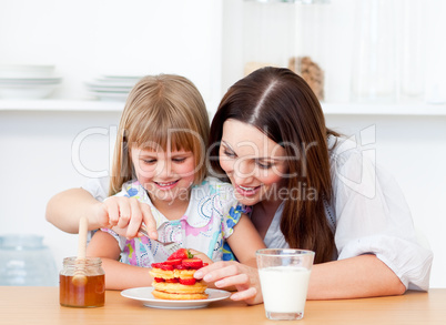 Merry little girl and her mother having breakfast