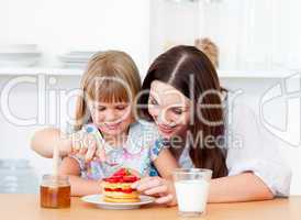 Merry little girl and her mother having breakfast