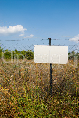 Blank white sign on a chain link fence.