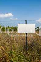 Blank white sign on a chain link fence.