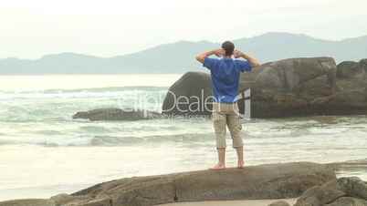 Mann entspannt auf einem Felsen am Meer