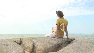 Frau entspannt auf Felsen am Meer