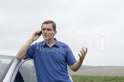 Mann telefoniert verärgert neben Auto