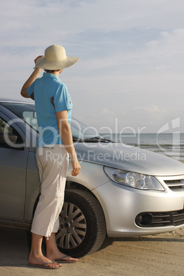 Frau steht neben Auto auf Strand