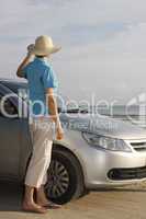 Frau steht neben Auto auf Strand