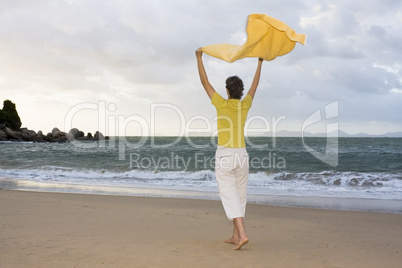 Frau mit Handtuch im Wind am Strand