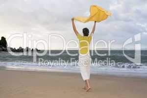 Frau mit Handtuch im Wind am Strand