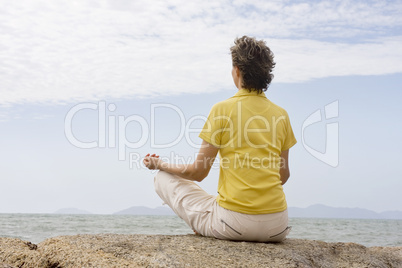 Frau meditiert am Meer