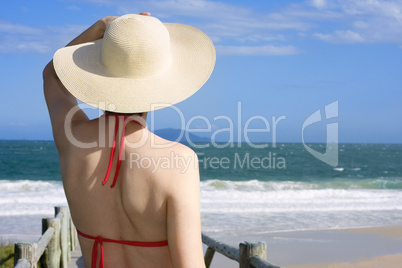 Frau mit Hut auf Steg am Meer