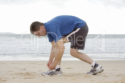 Läufer bindet sich die Schuhe am Strand