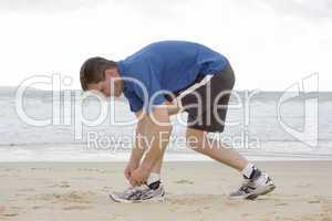 Läufer bindet sich die Schuhe am Strand