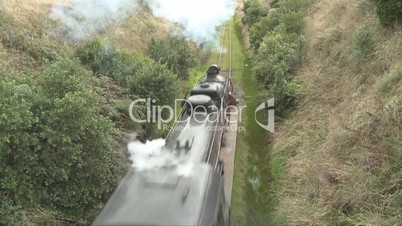 Steam train passes under overbridge