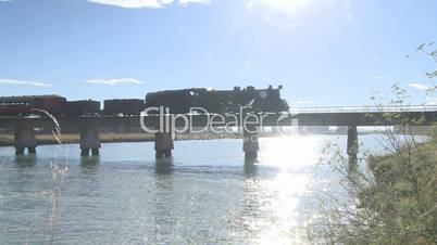 Steam train and carriages cross a bridge