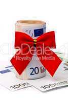 Roll of Euro money and red bow isolated on white background