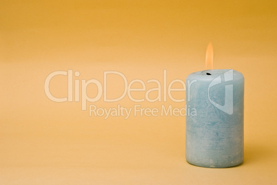 Burning candle over a yellow background