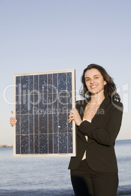 hübsche Frau hält einen Solarmodul vor einem blauen Himmel
