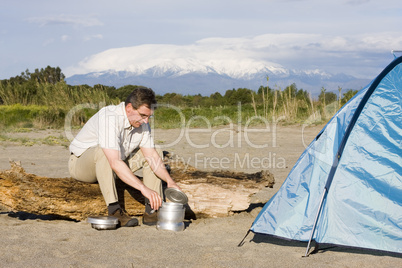 Mann neben Zelt vor Berg
