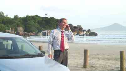 Geschäftsmann telefoniert neben Auto am Strand