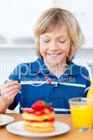 Adorable boy eating waffles with strawberries