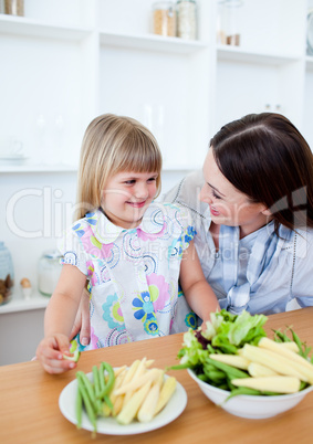 Attentive mother and her daughter eating vegetables