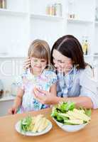 Smiling little girl eating vegetables with her mother