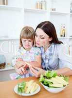 Dissatisfied little girl eating vegetables with her mother