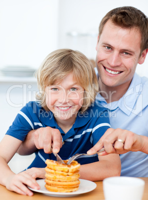 Smiling father and his son eating waffles