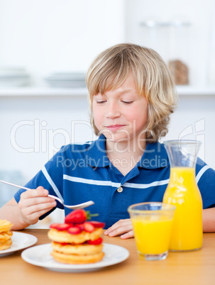 Cute boy eating waffles with strawberries