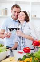 Smiling couple drinking wine while cooking