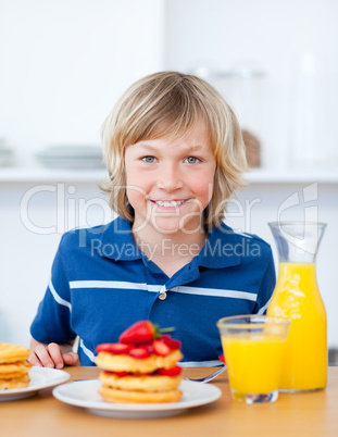 Smiling boy eating waffles with strawberries
