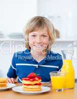 Smiling boy eating waffles with strawberries