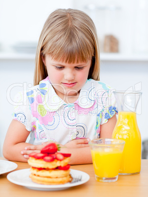 Cute little girl eating waffles with strawberries