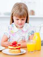 Cute little girl eating waffles with strawberries