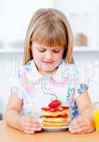 Adorable little girl eating waffles with strawberries