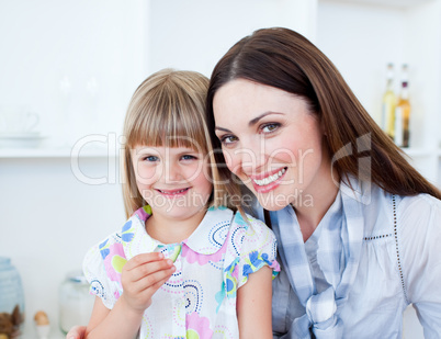 Caring mother and her daughter eating vegetables