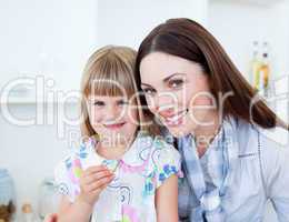 Caring mother and her daughter eating vegetables