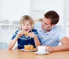 Charming father and his son eating waffles