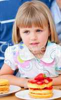 Cute little girl eating waffles with strawberries