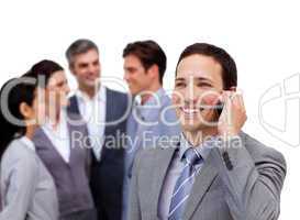 Handsome businessman on phone standing apart from his team