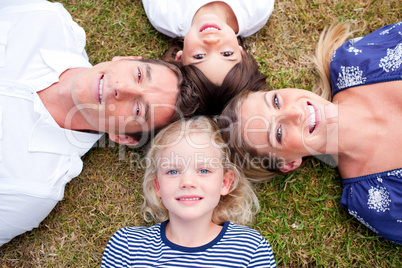 Loving family lying in circle on the grass