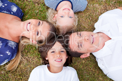 Cheerful family lying in circle on the grass