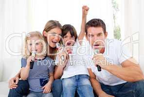 Portrait of a lively family singing through microphone