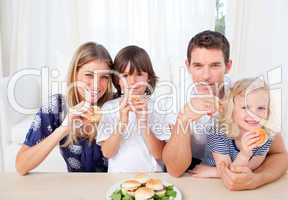 Smiling family eating burgers in the living room