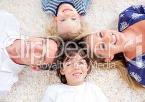 Cheerful family lying in circle on the wall-to-wall carpet