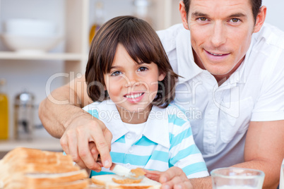 Portrait of a father and his son spreading jam on bread
