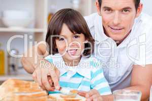 Portrait of a father and his son spreading jam on bread