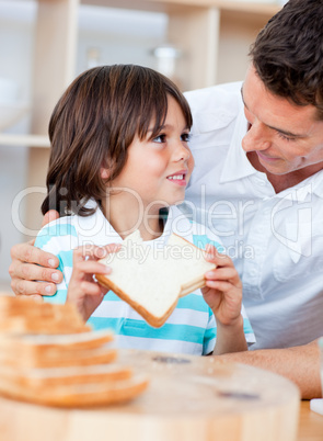 Adorable little boy and his father eating bread