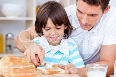 Loving father and his son spreading jam on bread